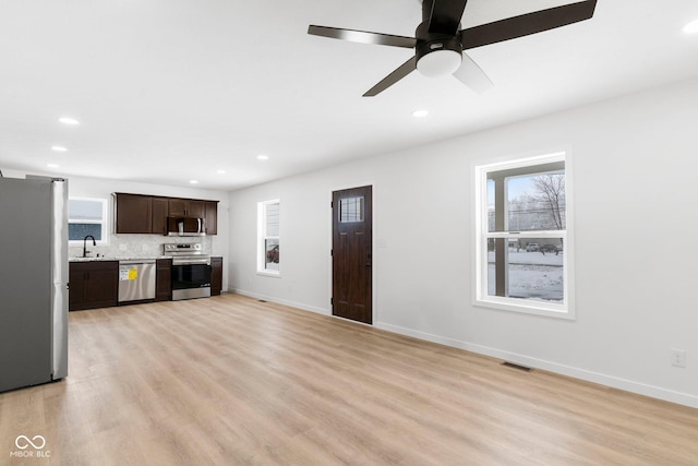 unfurnished living room featuring ceiling fan, sink, and light hardwood / wood-style floors