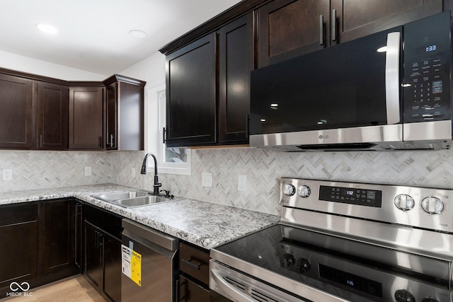 kitchen with light stone countertops, appliances with stainless steel finishes, dark brown cabinetry, sink, and light hardwood / wood-style flooring