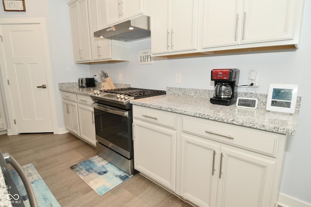 kitchen with stainless steel range with gas cooktop, white cabinets, light hardwood / wood-style floors, and light stone counters