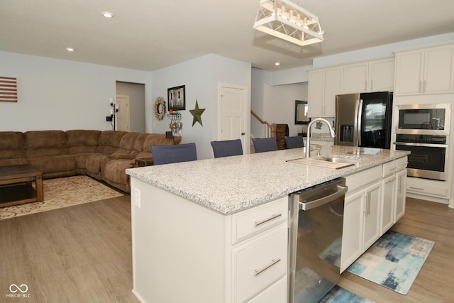 kitchen featuring sink, an island with sink, light hardwood / wood-style floors, and appliances with stainless steel finishes