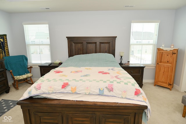 bedroom with multiple windows and light carpet