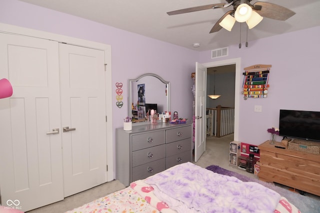 bedroom with ceiling fan, light colored carpet, and a closet