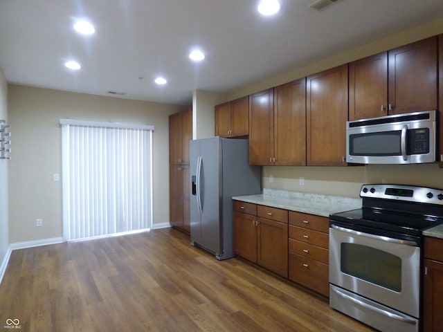 kitchen featuring hardwood / wood-style floors, light stone countertops, and stainless steel appliances