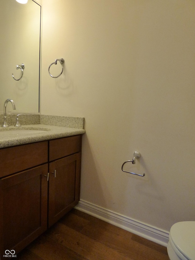 bathroom with hardwood / wood-style flooring, vanity, and toilet