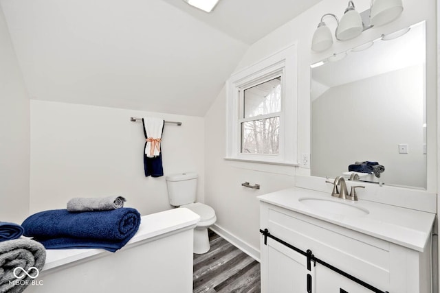 bathroom featuring toilet, wood-type flooring, vanity, and vaulted ceiling