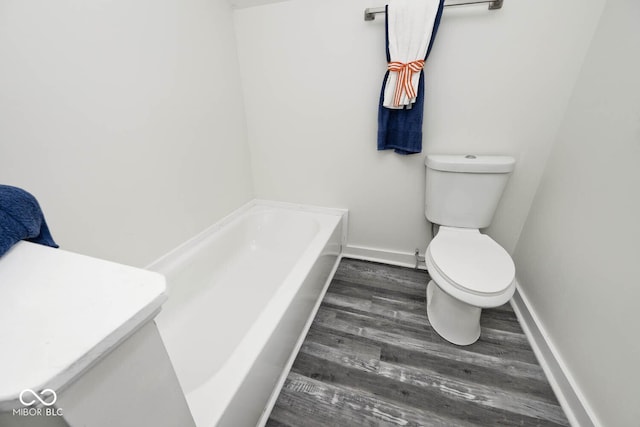 bathroom featuring a bathing tub, toilet, and hardwood / wood-style flooring