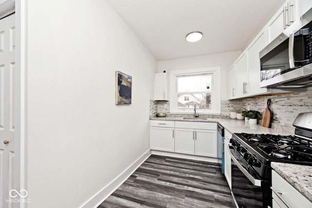 kitchen with sink, stainless steel appliances, tasteful backsplash, light stone counters, and white cabinets