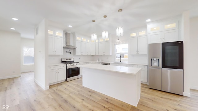 kitchen with stainless steel appliances, white cabinetry, wall chimney range hood, and a kitchen island