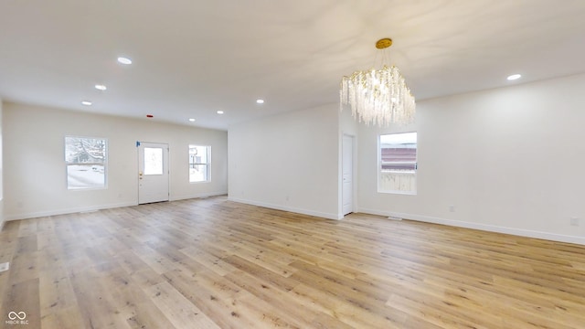 empty room featuring a notable chandelier and light hardwood / wood-style floors