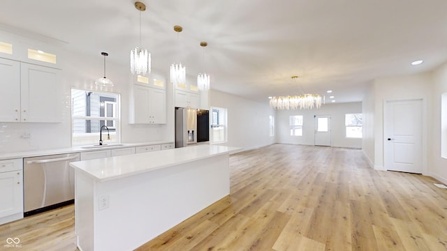 kitchen featuring pendant lighting, a center island, stainless steel appliances, white cabinets, and sink