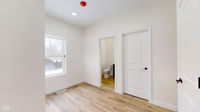 unfurnished bedroom featuring ensuite bathroom and light hardwood / wood-style flooring