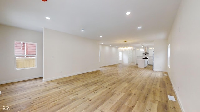 unfurnished living room featuring light hardwood / wood-style floors, plenty of natural light, and a notable chandelier