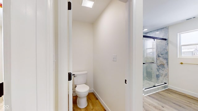 bathroom with toilet, a shower with door, and hardwood / wood-style flooring