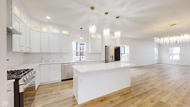 kitchen featuring stainless steel appliances, white cabinets, sink, and hanging light fixtures