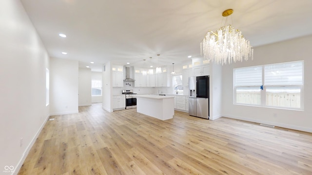 kitchen featuring an inviting chandelier, appliances with stainless steel finishes, a center island, white cabinetry, and decorative light fixtures