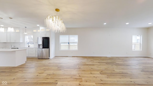 kitchen featuring decorative light fixtures, a notable chandelier, light hardwood / wood-style floors, stainless steel refrigerator with ice dispenser, and white cabinets