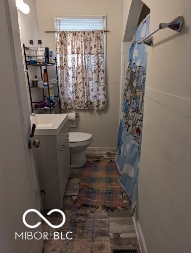 bathroom featuring toilet, vanity, and walk in shower