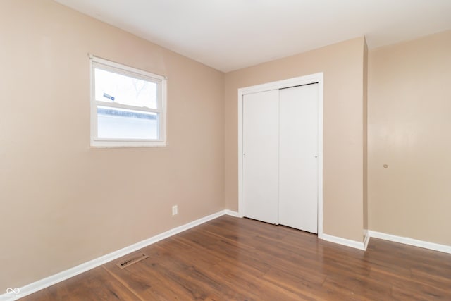 unfurnished bedroom featuring a closet and dark hardwood / wood-style floors