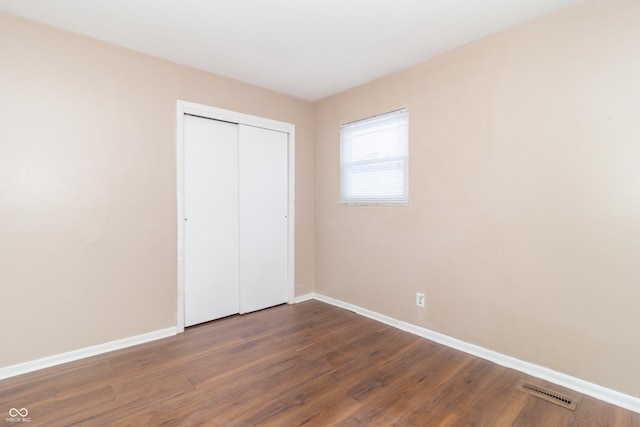 unfurnished bedroom with dark wood-type flooring and a closet