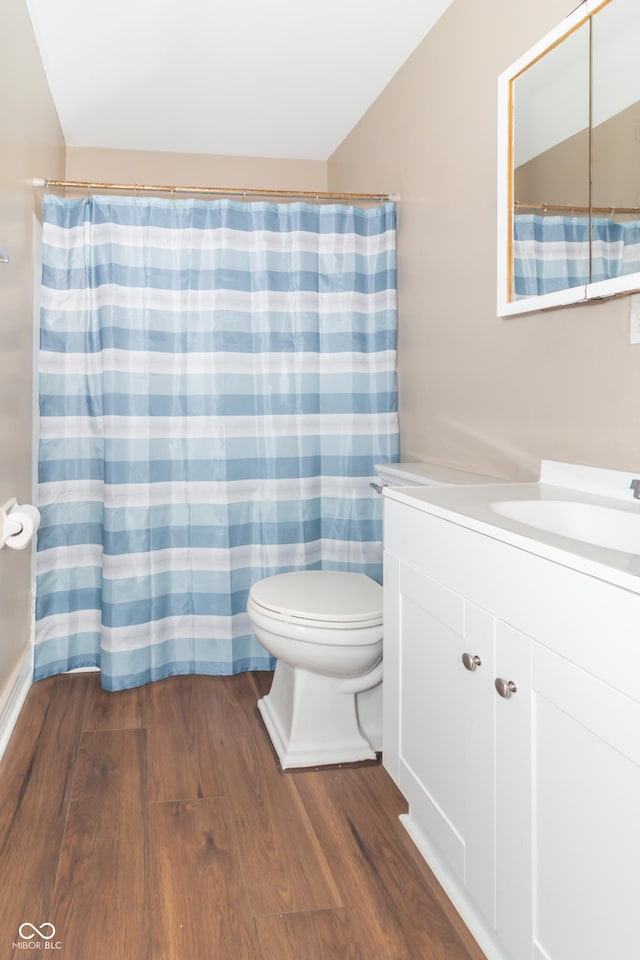 bathroom featuring hardwood / wood-style floors, toilet, vanity, and vaulted ceiling