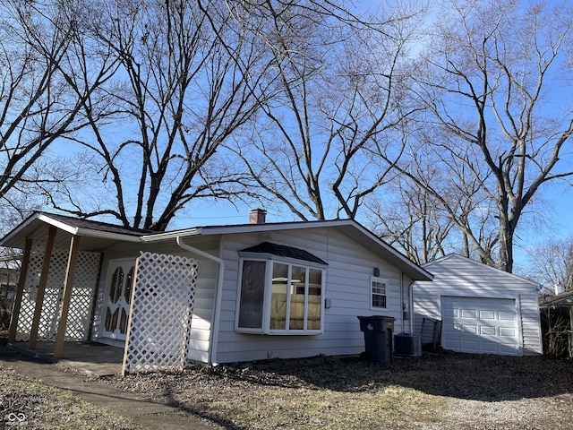 view of front of home featuring a carport, cooling unit, a garage, and an outdoor structure