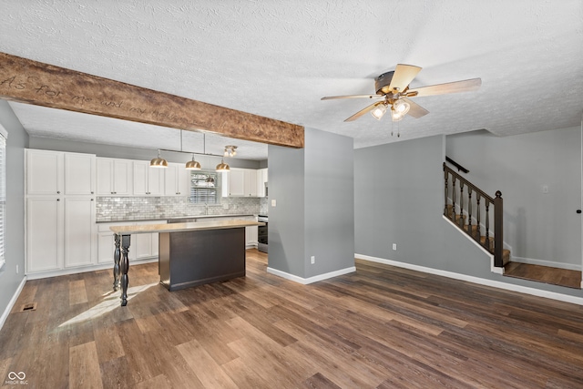 kitchen with pendant lighting, backsplash, dark hardwood / wood-style floors, white cabinets, and a kitchen island