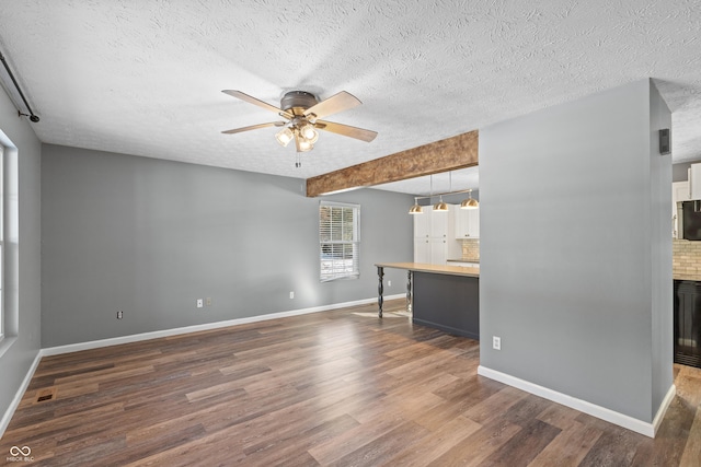 unfurnished living room with ceiling fan, dark hardwood / wood-style floors, a textured ceiling, and a fireplace