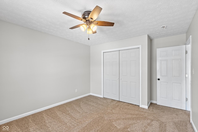 unfurnished bedroom featuring ceiling fan, carpet, a closet, and a textured ceiling