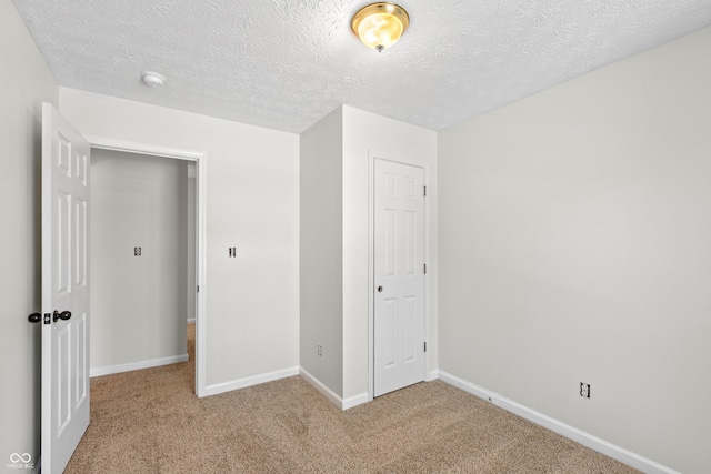 unfurnished bedroom featuring light carpet, a closet, and a textured ceiling