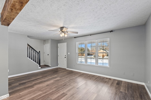 interior space featuring ceiling fan, dark wood-type flooring, and a textured ceiling