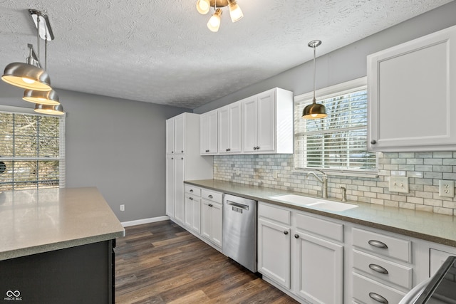 kitchen featuring pendant lighting, sink, dishwasher, white cabinetry, and decorative backsplash