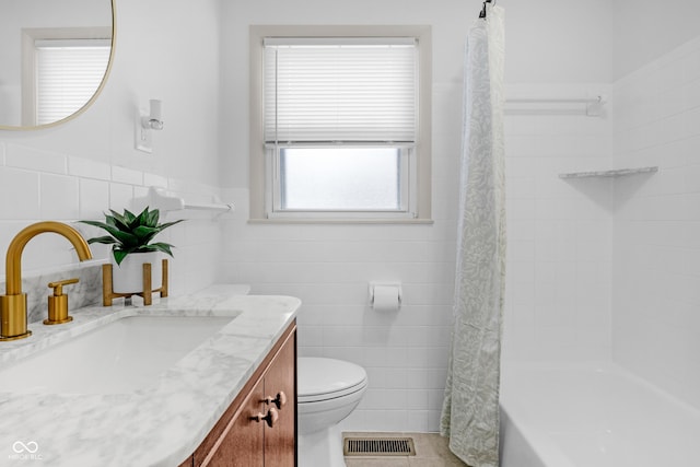 bathroom with tile patterned flooring, vanity, toilet, and tile walls