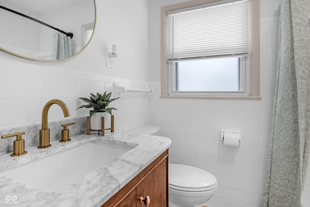 bathroom with vanity, toilet, and tile walls