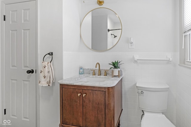 bathroom featuring vanity, toilet, and tile walls