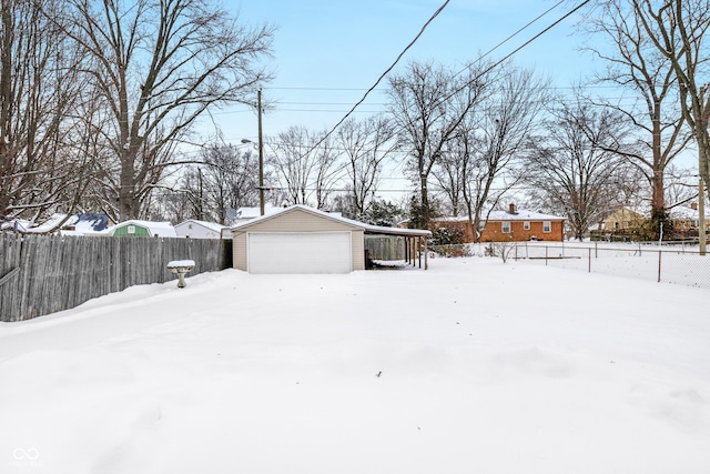 yard covered in snow featuring an outbuilding, a garage, and a carport