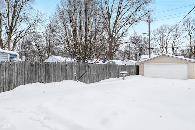 yard covered in snow with an outbuilding and a garage