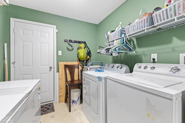 laundry area featuring a textured ceiling, washer and clothes dryer, and light tile patterned floors