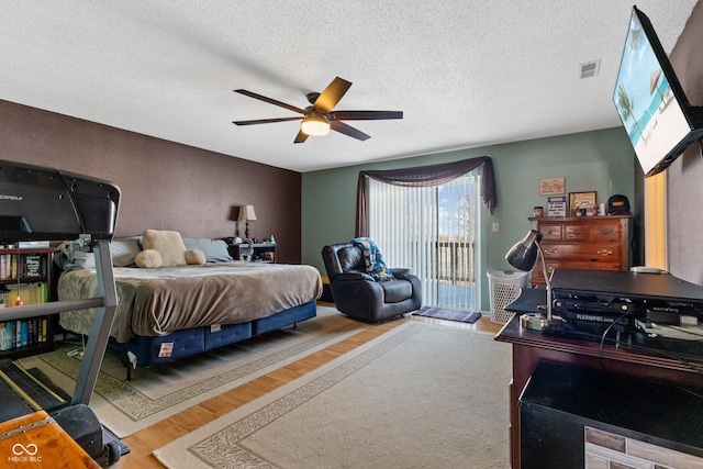 bedroom with a textured ceiling, ceiling fan, access to exterior, and hardwood / wood-style floors