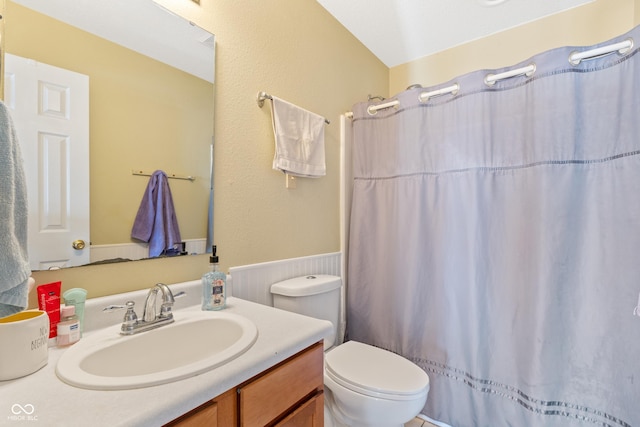 bathroom featuring toilet, a shower with shower curtain, vanity, and vaulted ceiling