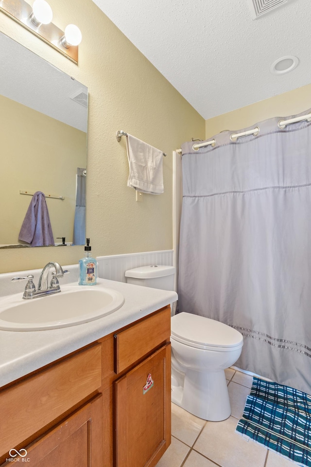 bathroom featuring a textured ceiling, tile patterned flooring, toilet, walk in shower, and vanity