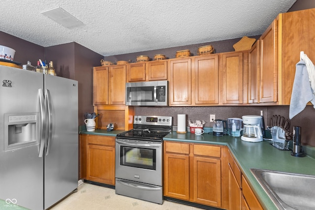 kitchen with stainless steel appliances, a textured ceiling, and sink