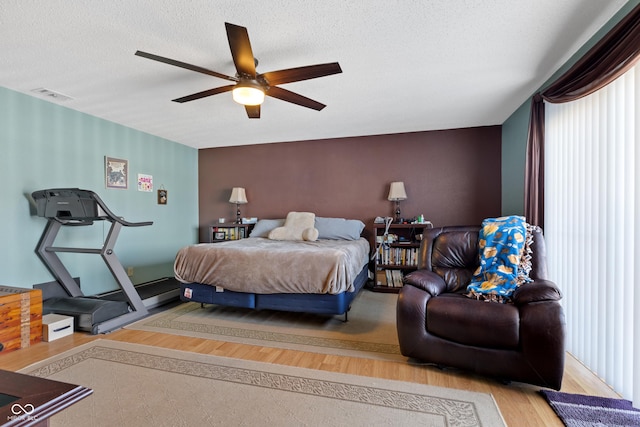 bedroom featuring a textured ceiling, ceiling fan, and wood-type flooring