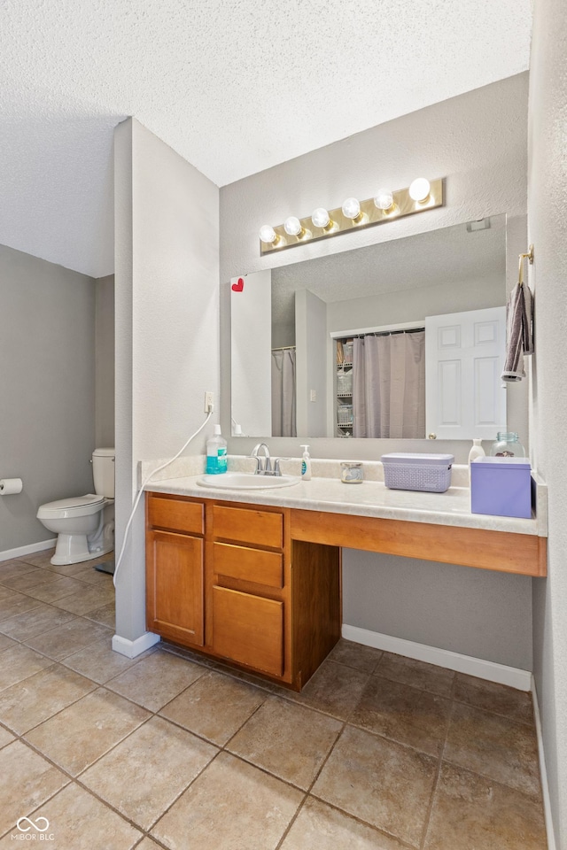 bathroom with toilet, vanity, and a textured ceiling