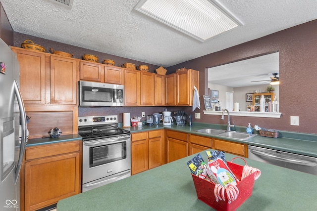 kitchen with sink, stainless steel appliances, a textured ceiling, and ceiling fan