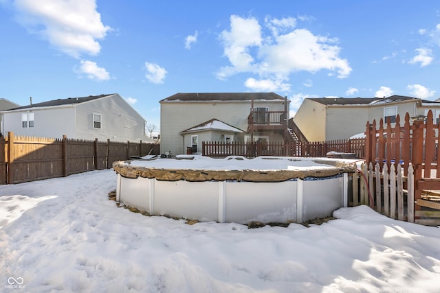 snow covered back of property featuring a covered pool