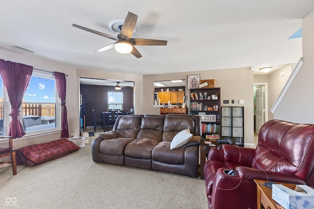 living room with a textured ceiling, ceiling fan, and carpet