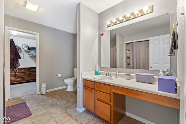 bathroom with a textured ceiling, tile patterned flooring, vanity, and toilet