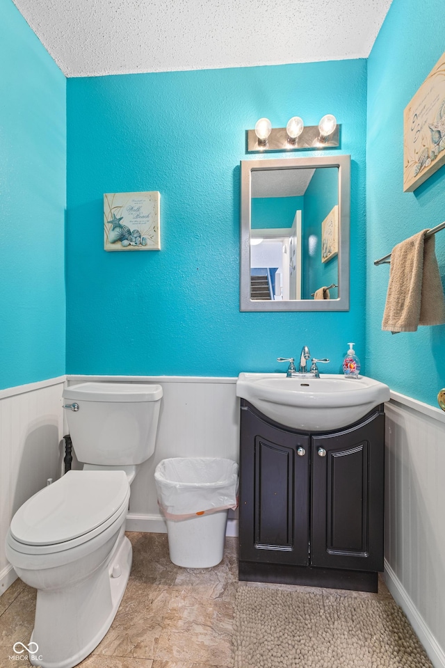 bathroom featuring toilet, a textured ceiling, and vanity