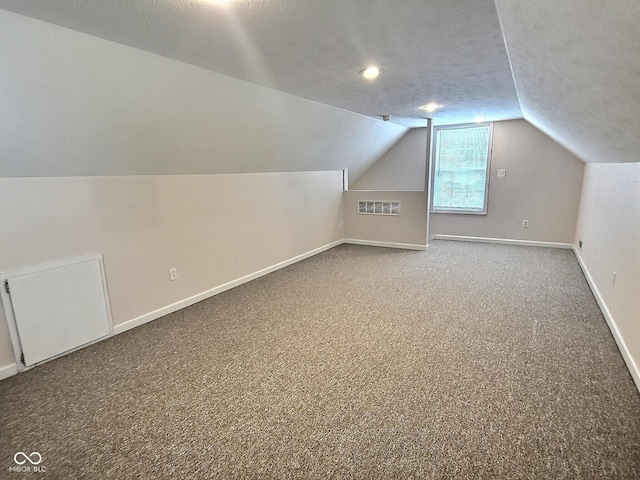 bonus room with carpet flooring, vaulted ceiling, and a textured ceiling