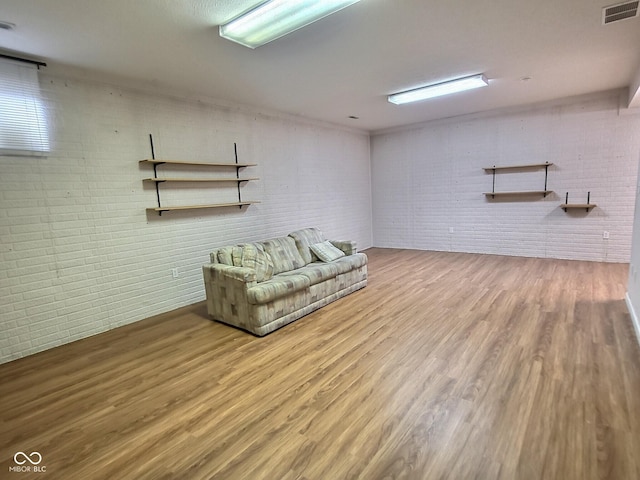 basement with wood-type flooring and brick wall